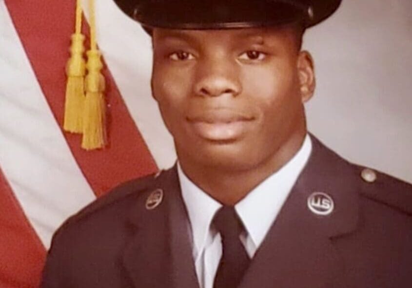 Portrait of a U.S. Air Force veteran in uniform, standing in front of the American flag.